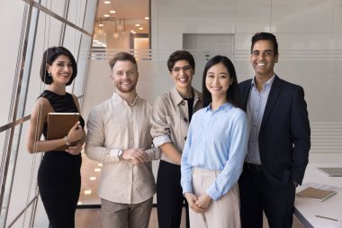 Pozitif iş arkadaşlarıyla dolu başarılı bir ekip ofis toplantı odasında çalışma alanında kameraya bakıyor, gülümsüyor, gülüyor, iş projesinin başarısından keyif alıyor, birlikte resim çektirmek için poz veriyorlar.