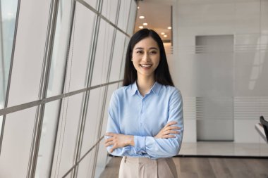 Neşeli, genç Asyalı yönetici kız kollarını kavuşturup gülümseyen kameraya bakarak modern iş dünyasında poz veriyor. Kadın profesyonel video çağrı ekranı portresi