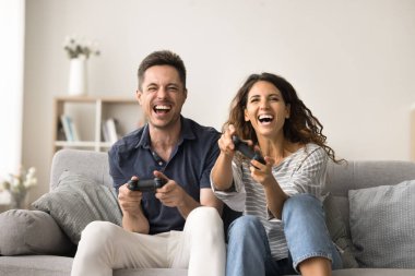 Mutlu çift video oyunu, sanal eğlence, oyun pedleri, oyun kontrolörlerinin tuşlarına basmak, bağırmak, gülmek, düğmelere basmak, kanepede oturmak, ön görüş