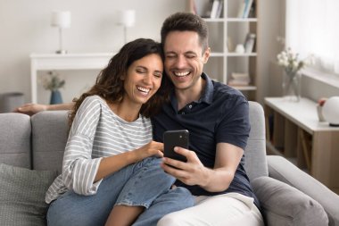 Mutlu bin yıllık mutlu karı koca internet iletişiminden keyif alıyor cep telefonunu birlikte kullanıyor, akıllı telefona bakıyor, selfie çekiyor, gülümsüyor, gülüyor.