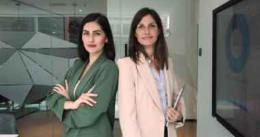İki güzel iş kadınının portresi, Avrupalı ve Latin kadın profesyoneller kameraya arka arkaya bakıyorlar. İşbirliği, başarılı iş ortaklığı, liderlik ve takım çalışması