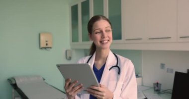 Klinikte çalışan tablet kullanan Latin kadın terapist, hasta geçmişini, laboratuvar sonuçlarını, ilaçlarını, tedavi planlarını gözden geçirmek için elektronik sağlık kayıtlarına erişmek, uygulamayla müşteriyle sohbet etmek