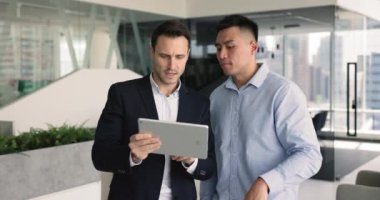 Asyalı ve İspanyol iş ortakları tablet cihazını kullanarak birlikte çalışarak, iş konularını araştırırken veya tartışırken yenilikçi kararlar veya fikirler üzerinde beyin fırtınası yaparak stratejik kararlar alırlar.