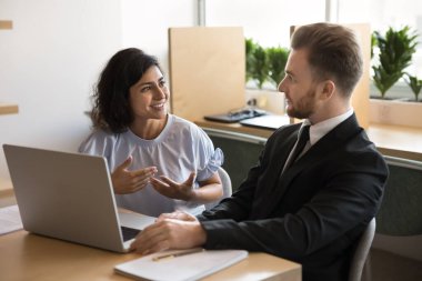 Pozitif bir çift Hintli ve Kafkasyalı ofis arkadaşı iş, iş görüşmeleri, bilgisayar başında takım çalışması, beyin fırtınası, ofis masasında oturmak, konuşmak...