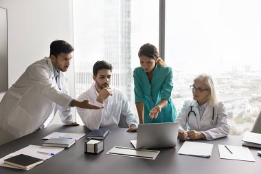 Çeşitli sağlık merkezleri doktorları tıbbi danışmanlık beyin fırtınası için bir araya gelirler. Çok ırklı doktor ekibi konseye bak bilgisayar ekranı çalışma hasta taraması tanı çözümleme sorunu