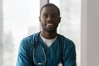 Portre başarılı bir Afro-Amerikan erkek profesyonel hemşire doktor gülümsemesi kameraya bakın. Cerrah üniforması konusunda güvenilir genç bir tıp uzmanı.