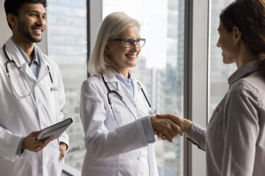 Görevli iki farklı doktor, başarılı iyileşme sürecinde olan genç bayanı tebrik etti. Hastaneden taburcu olan hastanın elini sıkın. Doktorlar ve sağlık sigortacısı el sıkışıyor. Ortaklığınız için teşekkürler.
