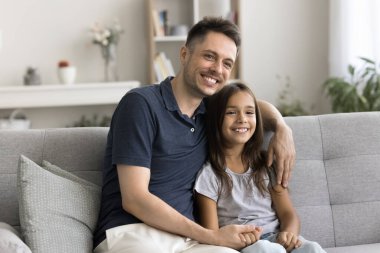 Babam her zaman önemser. Gülümseyen genç adam, üvey baba rahat koltukta rahatla kucakla, kucakla, kucakla, evlat edinilmiş küçük kız çocuğu sıcak sevgiyle elini tut, uzaktan düşün.