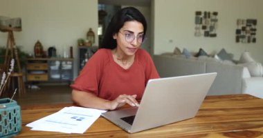 Mutlu Brezilyalı kadın dizüstü bilgisayarla masada oturuyor, e-posta okuyor, heyecan ve neşe gösteriyor, iyi haberler alıyor, önemli görevler başarıyor, maddi ödül ya da ikramiye alıyor, kişisel hedefe ulaşıyor.