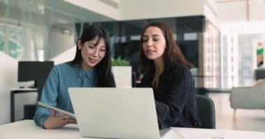 Çevrimiçi projede işbirliği yapan, masada oturan, verileri inceleyen, önemli belgeleri inceleyen, iş görüşmelerine katılan ve ofisteki başarılı takım çalışmalarına katılan iki genç kadın.