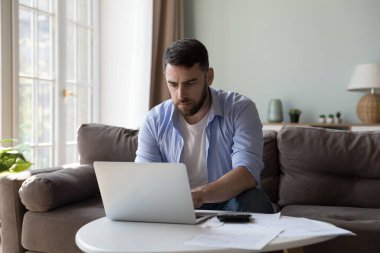 Evde çalışan, dizüstü bilgisayarda yazan, kanepede oturan milenyum çalışanı ile meşgul. Banka müşterisi faturaları ödemek için internet uygulamasını kullanıyor, yerli, mortgage, kira, vergi ücretleri