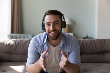 Mutlu olumlu milenyum blog yazarı, kablosuz kulaklıklı serbest çalışan portresi olan adam. Yetişkin koç, çalışan, iş adamı, video görüşmesinde konuşan, Webinar veren, koltukta oturan, kameraya bakan.