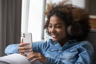 Afrikalı kızları kapat, kulaklıklarla müzik dinle, pisti seç, cep telefonundan eğlenceli içerikler izle. Gen Z modern teknoloji ve video çağrı kavramını kullan