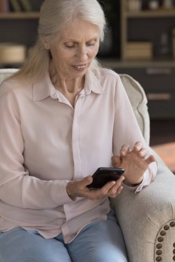 Olgun olgun bir kadının cep telefonuyla yazması, internet iletişimi için internet uygulaması kullanması, evden alışveriş yapması, arama yapması, arama yapması. Dikey çekim
