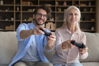 Neşeli yetişkin oğul ve son sınıf annesi sanal video oyunuyla heyecanlanıyor, oyun konsolu, sanal oyuncu, online yarışmada eğlenmek, aile eğlencesi, eğlenceli oyun zamanı