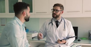 Genç İspanyol adam, erkek pratisyen hekimle el sıkışıyor tıbbi bakıma, danışmaya ve profesyonel tavsiyeye saygı duyduğunu söylüyor. Avrupa pratisyen hekimi hastane müşterisini ziyaret etti, tokalaştı, gülümsedi