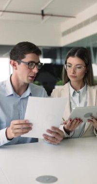 Tablet tutucu kağıtlar kullanarak, belgeleri inceleyerek, işle ilgili konuları veya ortak görevleriyle ilgili bilgileri tartışarak birlikte çalışan iki Avrupalı meslektaşı. Takım çalışması, profesyonel etkileşim