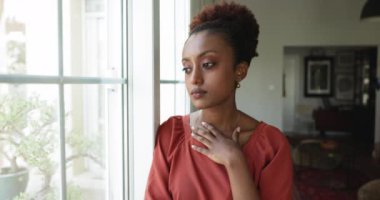 Düşünceli ya da sinirli Afrikalı kadın üzgün bir ifadeyle pencereden dışarı bakar, yalnız zaman geçirir, kişisel sorunları düşünür, ayrılır, kaybolur ya da birini bekler. Yalnızlık, yalnızlık, endişeler.