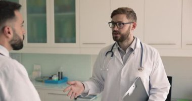 İki erkek doktor tartışır, bilgilerini ya da fikirlerini paylaşır, karşılıklı saygı jesti olarak el sıkışır, katkıda bulunur, sağlık hizmetlerinde başarılı olur, klinikte birlikte çalışırlar.