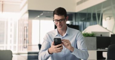 İş aktivitesi, bağlantı, mobil teknoloji. Modern ofis ortamında akıllı telefon kullanan, işle ilgili e-postaları inceleyen, cevap veren, arama bilgileri veren, iş dünyasının sosyal medya hesaplarını yöneten bir adam