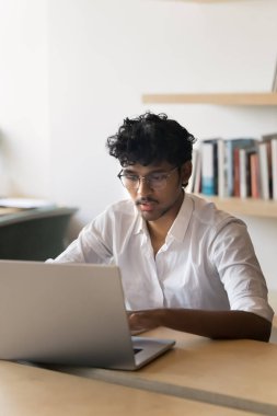Ofiste dizüstü bilgisayarda çalışan, masada oturan, daktilo yazan meşgul, genç Hintli iş adamı. Kütüphanede internet teknolojisi kullanan zeki bir erkek öğrenci. Dikey portre