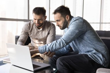 Birlikte çalışırken dizüstü bilgisayar kullanan iki meşgul iş adamı, çevrimiçi proje, uygulama, web servisi, web mağazası sunumu, ekranı işaret eden, konuşan, bilgisayarda konuşan