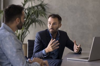 Ciddi iş adamı çalışanı, iş arkadaşı, dizüstü bilgisayarla iş yerinde konuşma, proje ortağına işbirliği şartlarını açıklama, danışma, iş arkadaşına tavsiye verme