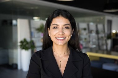 Ofis salonunda poz veren, kameraya bakıp gülümseyen Avrupalı, neşeli, genç ve güzel Arap girişimci kadın. Başarılı Orta Doğulu iş kadını profesyonel vesikalık portresi