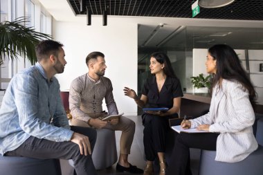 Çeşitli genç meslektaşlar iletişim için toplanıyor, birlikte çalışarak daireler çiziyor, takım çalışmasını, ortak çalışma görevlerini, proje planını, stratejiyi tartışıyorlar. Genç iş kadını grupla konuşuyor.