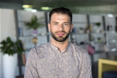İş yerinde rahat poz veren yakışıklı beyaz iş adamı vesikalık fotoğraf için kameraya bakıyor. Kendine güvenen yönetici, girişimci profesyonel portre