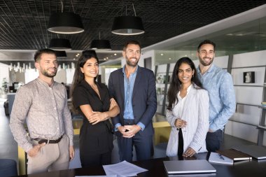 Ortak çalışma alanında profesyonel portre için poz veren pozitif etnik gruplu mutlu iş grupları. Çeşitli takımlar modern çalışma alanında birlikte duruyorlar, uzağa bakıyorlar, gülümsüyorlar, takım çalışmasını destekliyorlar.