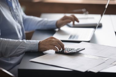 Bilinmeyen yetişkin muhasebeci çalışma masasında oturuyor faturalar, finansal belgeler, e-bankacılık yoluyla faturaları ödemek için bilgisayarla çalışıyor, kapat. Aile bütçe kontrolü, muhasebe işi kavramı