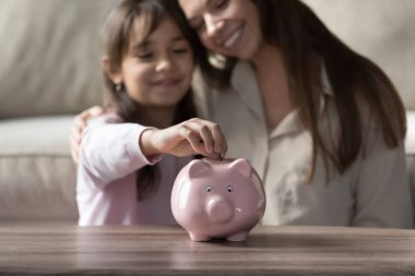 Mutlu bir anne ve tatlı bir kız çocuğu pembe seramik domuz kumbarasına para bırakıyor. Tasarruf yapmayı öğreniyor, yatırım yapıyor, gelecek eğitim ve alım için para biriktiriyor. Nesneye yaklaş