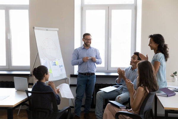 Happy satisfied business leader man getting applause from audience of employees after successful presentation. Diverse group applauding, clapping hands, thanking proud coach for training