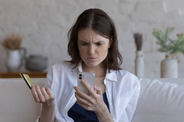 Kafası karışmış müşteri kız çevrimiçi ödemelerle, engellenmiş hesaplarla, elektronik cüzdanlarla, aşırı harcama bütçesiyle, kredi kartıyla, cep telefonuyla, ekranda kötü haberlerle karşı karşıya.