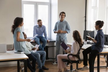 Genç Latin lider, çeşitli iş grupları toplantılarında iş arkadaşlarıyla konuşarak başlangıç projesini sunuyor. Şirket danışmanı, koç çalışanlara danışmanlık yapıyor.