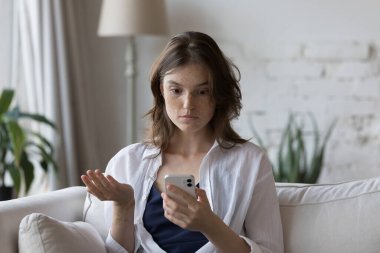 Endişeli cep telefonu kullanıcısı kız ekranı izliyor, akıllı telefon ekranına bakıyor, çevrimiçi uygulamayla ilgili sorunlar buluyor, kötü bağlantı, internet servisi, şaşırtıcı kötü haberler alıyor.