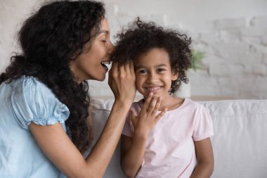 Neşeli siyah anne, heyecanlı küçük kıza sırrını söylüyor, kulağına fısıldıyor. Afrikalı çocuk kameraya bakıp gülüyor. Anne ve kızı arkadaşlığın, güvenin, evde eğlenmenin tadını çıkarıyorlar.