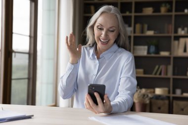 Mutlu, olgun 60 'ların kadını akıllı telefon ekranına el sallıyor, kameraya gülümsüyor, video konferans görüşmesinde konuşuyor, ailesiyle konuşuyor, torunlarıyla internetten konuşuyor, gülüyor.