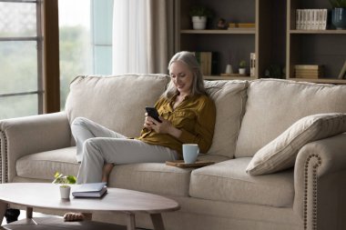 Neşeli, beyaz saçlı, evde cep telefonu kullanan, mesaj yazan, sabah kahvesi, çay, eğlence zamanı, internet, alışveriş...