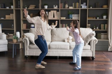 Heyecanlı mutlu dansçı anne ve neşeli aktif çocuk evde oturma odasında dans ediyor, gülüyor, şarkılar söylüyor, eğleniyor, eğleniyor, eğleniyor, eğleniyor, eğleniyor, enerjik oyun zamanı, aile partisi. Geniş açı