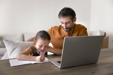 Pozitif odaklı Latin baba, küçük kızın okul ödevlerini yapmasına yardım ediyor. Yanında oturuyor, bilgisayarında not defterine mektuplar yazıyor, metni dikte ediyor, test için hazırlanıyor.