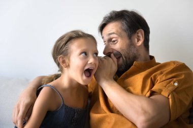 Neşeli baba heyecanlı küçük çocuğu şaşırtıyor, kızların kulağına inanılmaz gizli haberler fısıldıyor. Heyecanlı kız mutlu Latin babayı dinliyor, şok içinde ağzını açıyor, heyecan içinde.