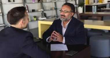 Olgun Hintli İK yöneticisi elinde özgeçmiş kağıdıyla masada oturuyor, başarılı bir iş görüşmesiyle erkek başvuruyu kutluyor, şirket ofisinde el sıkışarak resmi toplantıyı bitiriyor. Personel