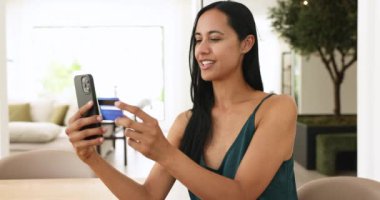 Gülümseyen milenyum kadını, elinde kredi kartı ve telefonla elinde telefonla gezici uygulama üzerinden alışveriş yapıyor, pazar sitelerini kullanıyor, basit ekspres e-hizmetlerin keyfini çıkarıyor, modern uygulama üzerinden para aktarıyor.
