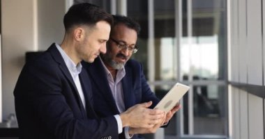 Dijital tablet üzerinde iş başvurusu veya programı kullanırken tartışan iki işadamı, iş ile ilgili konuları ofiste ele alın, mali raporları gözden geçirin, karı analiz edin. Takım çalışması.