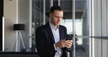 İş yerinde cep telefonu kullanan 40 'lı yaşlardaki ciddi işadamı, meslektaşlarıyla uzaktan iletişim kuruyor, proje ilerlemesini takip ediyor, müşteri soruşturmalarına cevap veriyor, araştırma yapıyor, pazar eğilimlerini izliyor