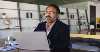 Düşünceli, olgun Hintli iş adamı arama sorunu çözümü, beyin fırtınası, sunum hazırlama, rapor hazırlama, çalışma alanında dizüstü bilgisayarla otur. Modern teknoloji, analitik iş, yazılım kullanan çalışma akışı