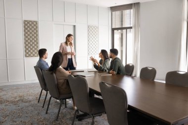 Ciddi bayan patron büyük ofis toplantı masasında çeşitli çalışanlarla konuşuyor, bir grup yöneticiyle satış raporlarını tartışıyor. Takım çalışması için çalışma sahasında çok ırklı iş adamları toplantısı