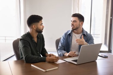 Kendine güvenen genç Arap iş ortakları online girişimde birlikte çalışıyorlar, iş yerinde bilgisayarla konuşuyorlar, kurumsal iletişimi tartışıyorlar. Akıl hocası stajyeri.